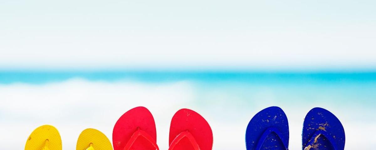 natikači različnih barv, zapičeni v pesek, z modrim morjem v ozadju